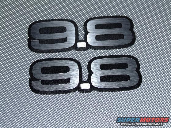 Two black and silver "9.8" emblems on a textured gray surface