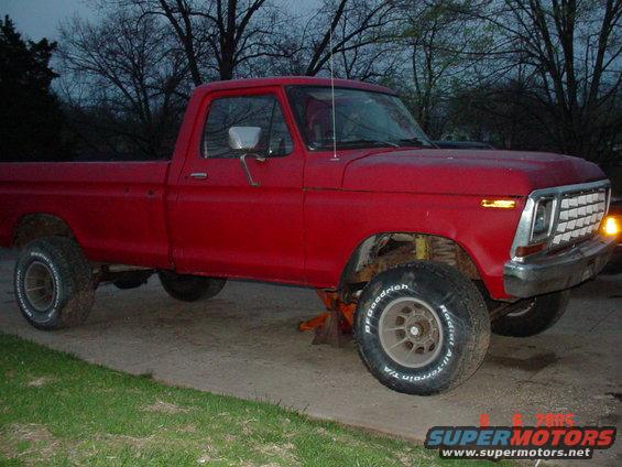 Red pickup truck with BFGoodrich tires, jacked up on the front right side