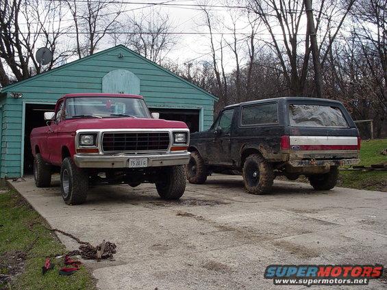 Black 1988 Ford Bronco parked next to a red Ford pickup truck