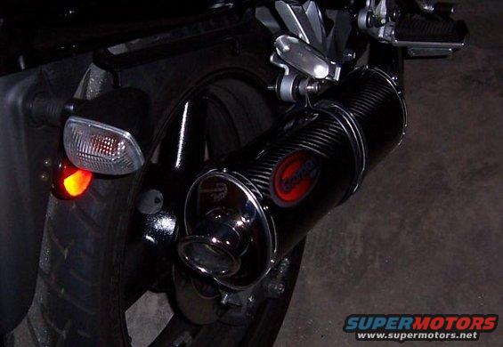 Close-up of a black motorcycle exhaust pipe with a red logo