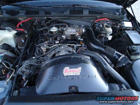 Engine bay with Summit Racing CAUTION FAN cover and SuperMotors watermark