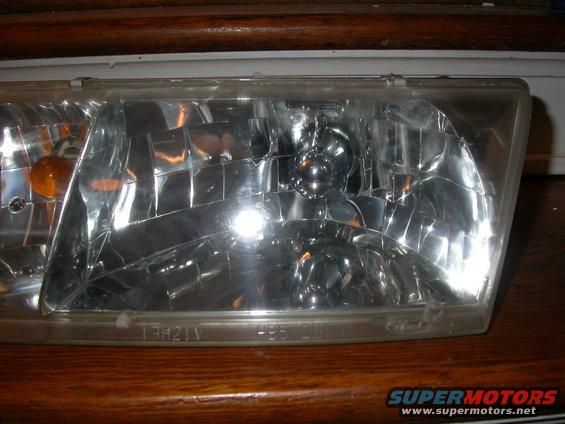 Close-up of a clear headlight assembly with an amber turn signal bulb visible
