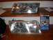 1998 Mercury Grand Marquis - A headlight restoration kit sits next to two car headlights on a wooden surface.