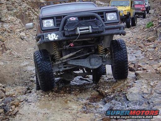 1986 Ford Bronco II with winch and aftermarket bumper on rocky trail, yellow Jeep and red Jeep behind