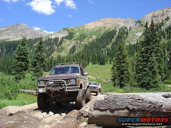 Brown Ford Bronco II with off-road modifications on a rocky mountain trail