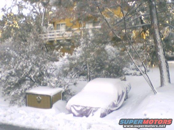 car covered in snow next to a chest, house in background