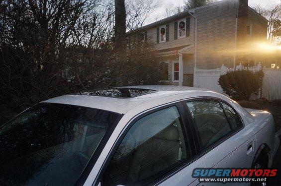 Silver sedan with sunroof parked in front of a house