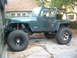 1994 Jeep YJ - This modified Jeep Wrangler is shown from the side, large off-road tires and a visible roll cage.