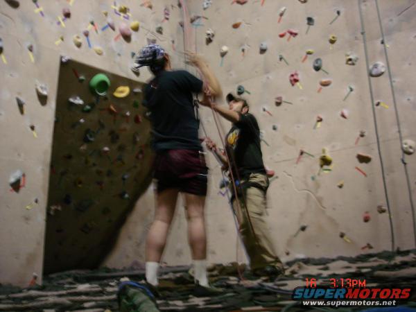 Indoor climbing wall with colorful holds, two climbers, and a timestamp in the corner