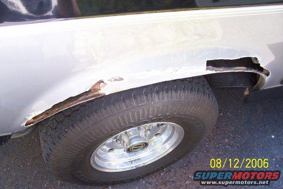 Close-up of severe rust damage on the rear wheel well of a vehicle