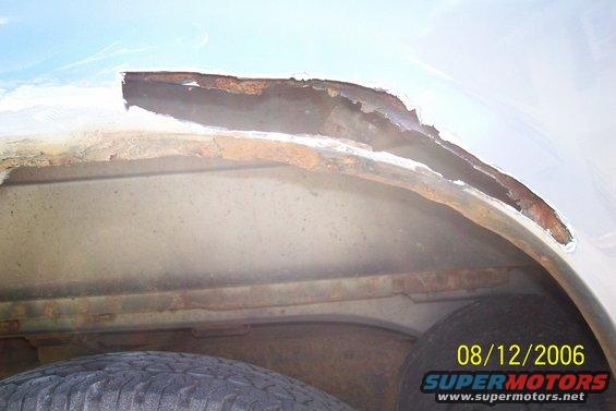 Rusted wheel well interior with visible tire and date stamp 08/12/2006