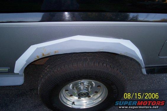 Gray and black SUV rear wheel well showing rust and bodywork