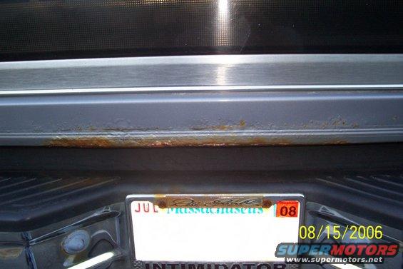 Rear bumper area with rust on the trim above the license plate. Massachusetts plate visible