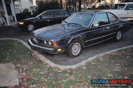 Dark blue BMW E24 coupe parked next to a black sedan and a white pickup truck