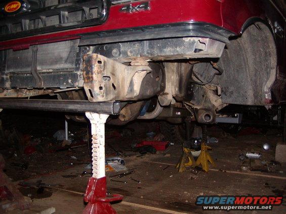 Red 1991 Ford Bronco front end on jack stands, showing suspension and frame