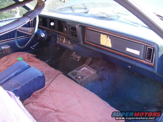 Blue interior with wood trim dashboard and a sticker on the dash