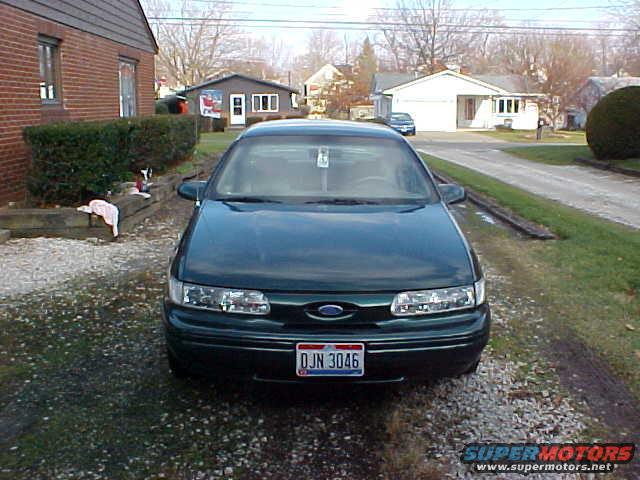 Front view of dark green Ford Taurus sedan on a gravel driveway