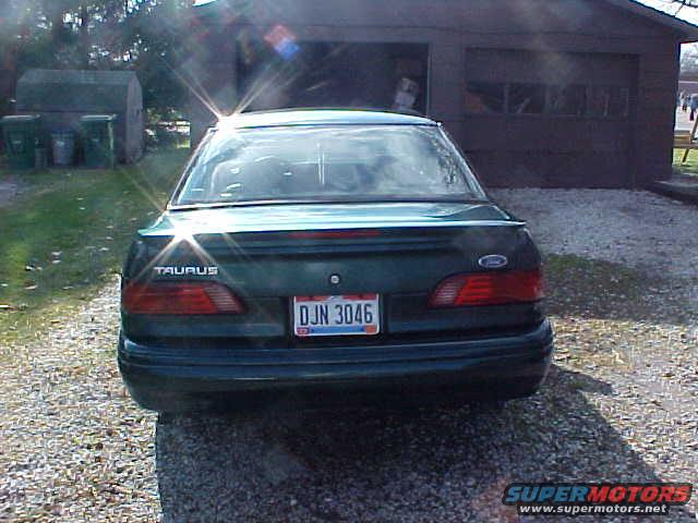 Rear view of dark green Ford Taurus sedan in front of a garage