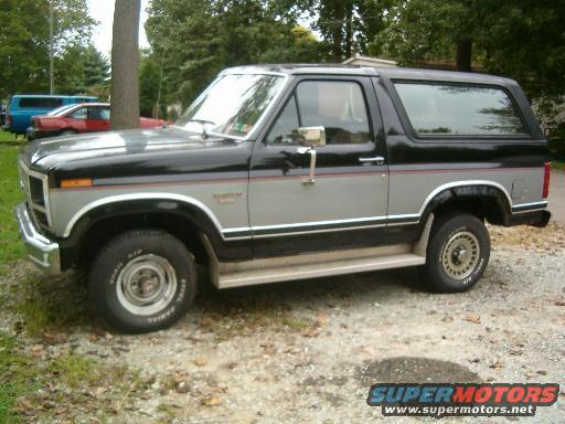 Two-tone black and silver Ford Bronco with chrome trim, parked on gravel