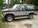 1986 Ford Bronco - A two-tone black and silver Ford Bronco is parked outdoors with other vehicles in the background.