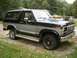 1986 Ford Bronco - This two-tone SUV features a prominent chrome grille and side trim, suggesting an early 1980s model.