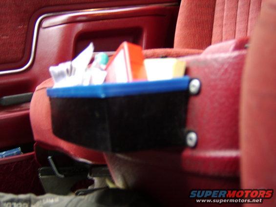 Red fabric interior with a black organizer holding tissues and a red box attached to the seat