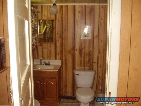 Bathroom with wood-paneled walls, a sink, and a toilet