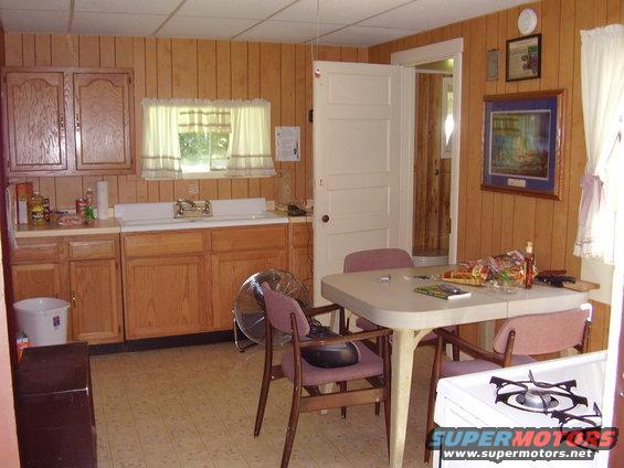 Kitchen with wood paneling, table, chairs, stove, and cabinets