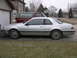 1988 Ford Thunderbird - A silver coupe with a two-door body style is parked in front of a garage, with a red SUV behind it.