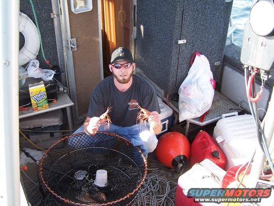 man on boat holding shrimp, with fishing gear and supplies