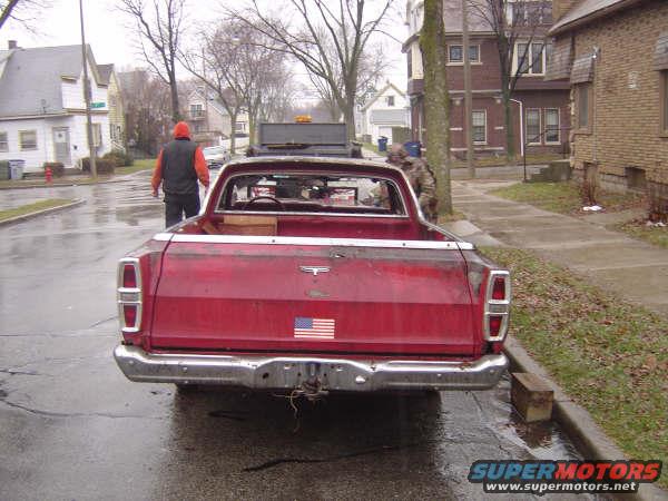 Rear view of a red pickup truck with an American flag sticker on the tailgate