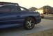 1994 Dodge Stealth - A blue sports coupe is parked on a concrete driveway in front of houses.