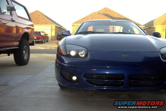 Blue sports car front view, parked next to a lifted truck
