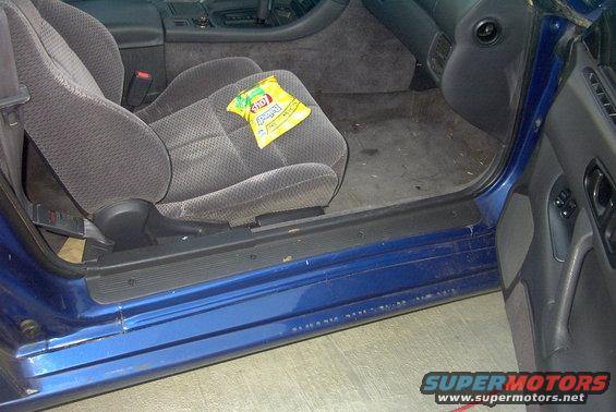 Car interior showing passenger seat with a bag of chips on it. Blue door frame visible