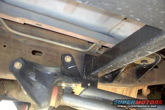 Underside view of a vehicle frame with black sliders attached