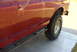 1994 Ford Bronco - Side view of a red SUV with a slider bar and off-road tire, showing minor body damage.