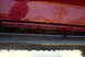 1994 Ford Bronco - Close-up of a red vehicle's body panel and black slider, with water droplets visible.