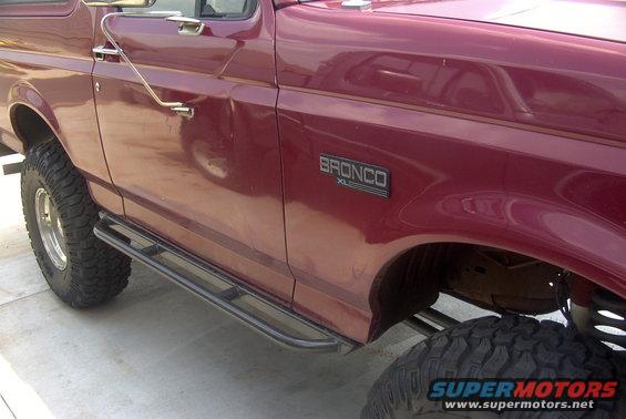 Side view of a maroon Ford Bronco XL with aftermarket side steps and large tires