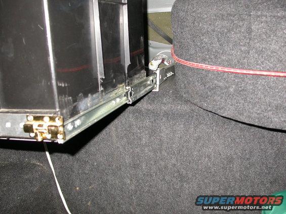 Close-up of a trunk drawer slide mechanism with a black drawer box and gray carpeted side panel