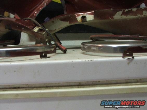 Red car parts with chrome trim and wiring, on a white surface