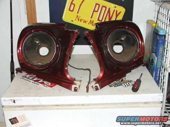 Pair of red fender extensions with headlight openings, one with a screwdriver