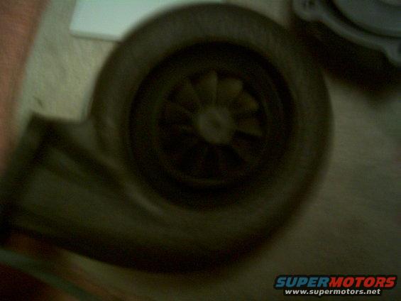 Turbocharger housing with visible impeller blades, dark color, close-up view