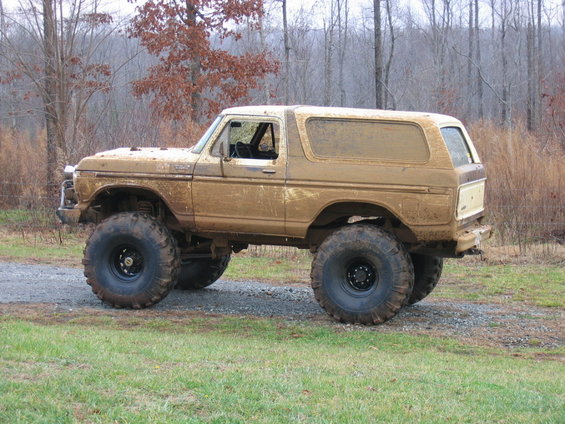 Mud-covered lifted SUV with large tires, side view