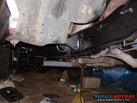 Underside view of vehicle frame and suspension, with parts on jack stands