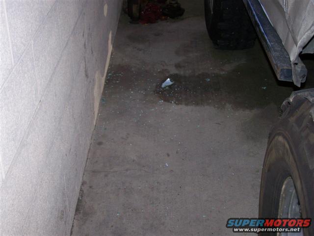 Side view of a vehicle tire and lower body panel, with debris on the ground