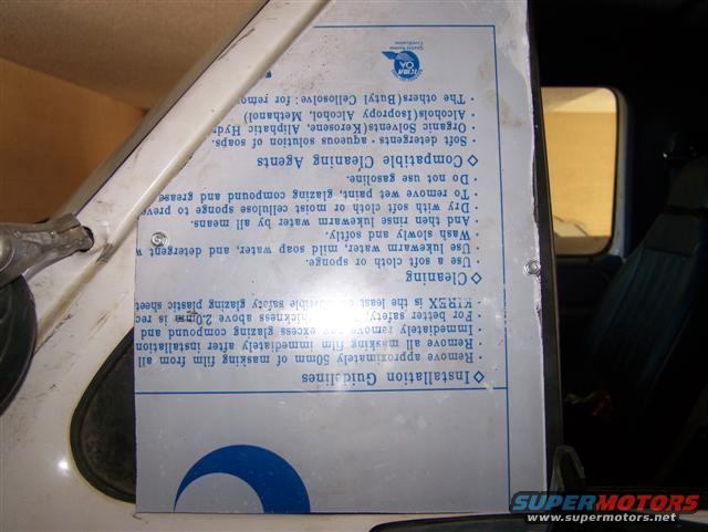 Inside of a vehicle, showing a document with cleaning and installation instructions taped to the door or window