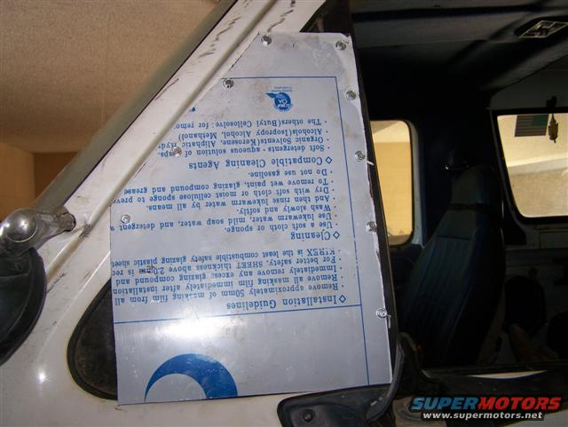Interior of a white vehicle with a metal plate on the door frame showing cleaning instructions