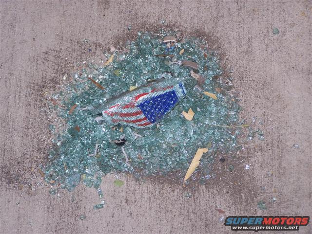 Pile of shattered glass on concrete with a fragment of an American flag