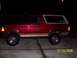 1994 Ford Bronco - A red 1994 Ford Bronco is shown parked on a concrete surface at night, a lifted suspension and off-road tires.