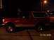 1994 Ford Bronco - This red Ford Bronco with a white top is viewed from the side at night.